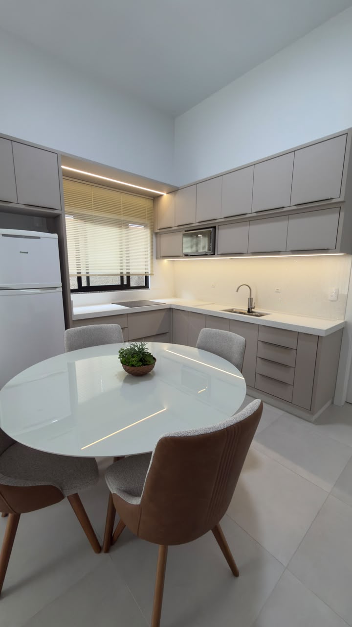 Cozinha planejada com bancada branca, cooktop e cuba embutida