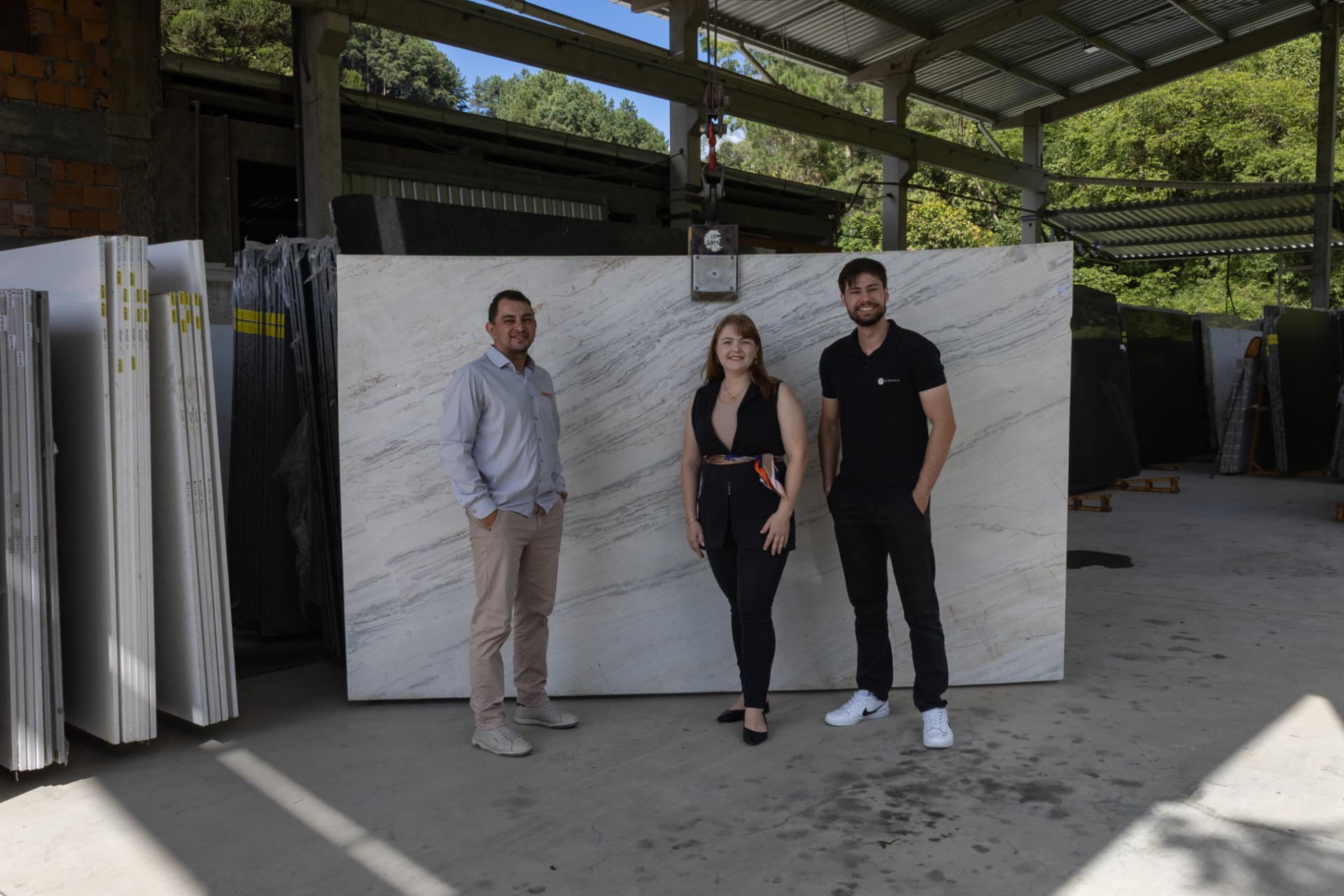 Equipe Hedel ao lado de uma chapa de quartzito no depósito